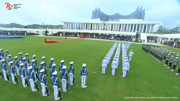 Presiden Republik Indonesia Joko Widodo (Jokowi) memimpin Upacara Peringatan Detik-Detik Proklamasi Kemerdekaan Republik Indonesia ke-79 Tahun 2024 di Lapangan Upacara Istana Negara Ibu Kota Nusantara (IKN), Kabupaten Penajam Paser Utara, Provinsi Kalimantan Timur, pada Sabtu (17/08/2024) pagi. Pada upacara tahun ini, Presiden Jokowi memimpin dari Istana Negara Nusantara, sementara Wakil Presiden Ma’ruf Amin memimpin dari Istana Merdeka, Jakarta. Sebelum upacara dimulai, prosesi kirab duplikat bendera pusaka Sang Merah Putih dan Naskah Teks Proklamasi dilakukan dari ruang penyimpanan di Ruang Bendera Istana Negara IKN menuju meja dan mimbar kehormatan oleh Purna Paskibraka Duta Pancasila 2023. Adapun yang bertindak sebagai komandan upacara adalah Kolonel Infanteri Nur Wahyudi, Komandan Satuan 81 Kopassus. Upacara diawali dengan tembakan meriam sebanyak 17 kali, diikuti dengan bunyi sirine selama satu menit. Ketua Dewan Perwakilan Rakyat Republik Indonesia (DPR RI), Puan Maharani, membacakan Naskah Proklamasi. Setelah itu, Presiden selaku inspektur upacara memimpin penghormatan untuk mengheningkan cipta. “Untuk mengenang jasa para pahlawan dan pejuang bangsa, khususnya pendiri bangsa, Bapak Bung Karno dan Bung Hatta, mengheningkan cipta dimulai,” ucap Presiden yang diikuti oleh seluruh peserta upacara. Setelah mengheningkan cipta, Menteri Agama Yaqud Cholil Qoumas memandu pembacaan doa. Kemudian, Tim Paskibraka Nusantara Baru, yang merupakan bagian dari 76 anggota Paskibraka 2024, dengan khidmat menjalankan tugas pengibaran bendera Sang Merah Putih. Pertunjukan kesenian di Lapangan Upacara Istana Negara IKN dan Halaman Depan Istana Merdeka Jakarta turut memeriahkan Upacara Peringatan Detik-Detik Proklamasi Kemerdekaan Republik Indonesia ke-79 Tahun 2024. Turut hadir mengikuti upacara dari Lapangan Upacara Istana Negara IKN dan Halaman Depan Istana Merdeka Jakarta, di antaranya Ibu Negara Iriana Joko Widodo, Wury Ma’ruf Amin, Menteri Pertahanan (Menhan) Prabowo Subianto, Sekretaris Kabinet (Seskab) Pramono Anung, Menteri Sekretaris (Mensesneg) Negara Pratikno dan para Menteri Kabinet Indonesia Maju serta tamu undangan Read more: https://setkab.go.id/presiden-jokowi-pimpin-upacara-peringatan-detik-detik-proklamasi-di-istana-negara-ikn/