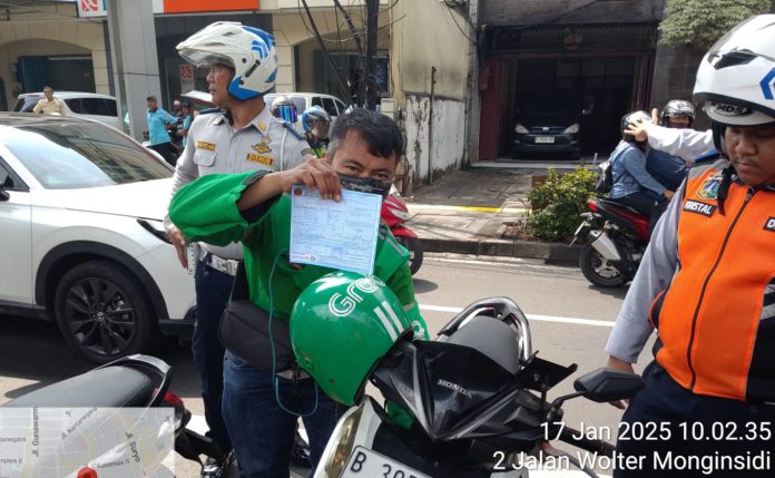 Petugas memberikan sanksi tilang kepada pengendara motor karena parkir liar di trotoar Jalan Wolter Monginsidi, Jakarta Selatan, Jumat (17/1/2025).