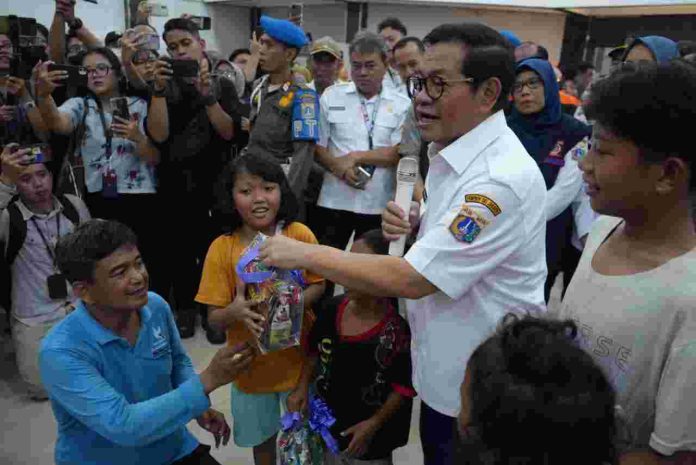 Gubernur Jakarta Pramono Anung membagi hadiah kepada anak-anak saat meninjaau lokasi pengungsian banjir di GOR Otista, Jakarta Timur, Kamis (6/3/2025).