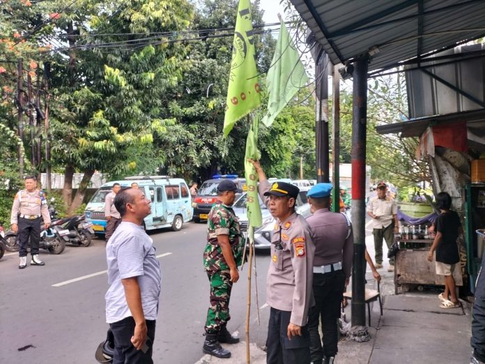 Petugas kepolisian menurunkan bendara ormas di Jakarta Pusat, Sabtu (10/5/2025).