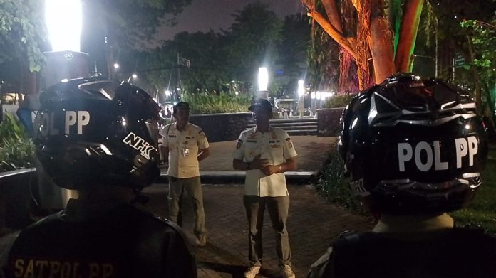 Satpol PP melakukan penjagaan di Taman Langsat, Kebayoran Baru. Penjagaan dilakukan untuk mengawasi pengunjung agar tidak berbuar mesum pada malam hari. 