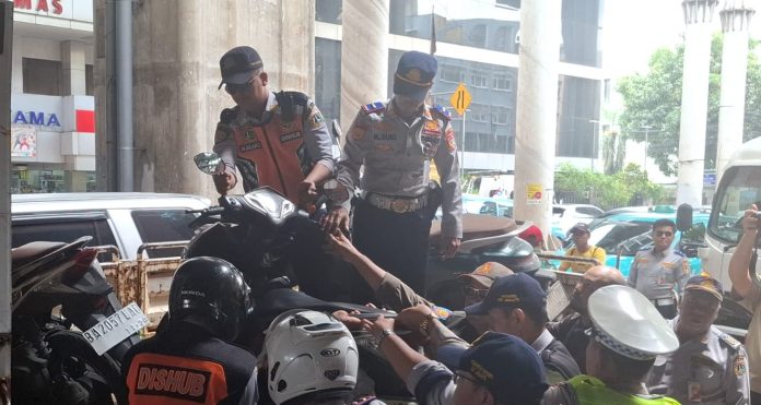 Petugas gabungan kembali menertibkan parkir liar di depan ITC Cipulir, Jalan Ciledug Raya, Kebayoran Lama, Jakarta Selatan, Kamis (12/4/2026).  Dalam operasi gabungan ini, sebanyak 14 sepeda motor yang kedapatan parkir sembarangan di badan jalan langsung diangkut petugas.