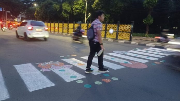 Warga menggambar ulang zebra cross di Jalan Supomo, Tebet, Jakarta Selatan dengan karakter unik “Pic-Man” setelah laporan hilangnya fasilitas tersebut tidak mendapat respons melalui aplikasi JAKI selama lebih dari satu tahun.