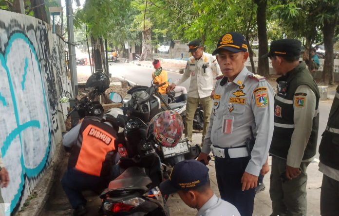 Satuan Pelaksana Dinas Perhubungan (Satpel Dishub) Kecamatan Kebayoran Baru, Jakarta Selatan, menertibkan kendaraan yang parkir sembarangan melalui operasi cabut pentil (OCP), Jumat (30/10/2026).